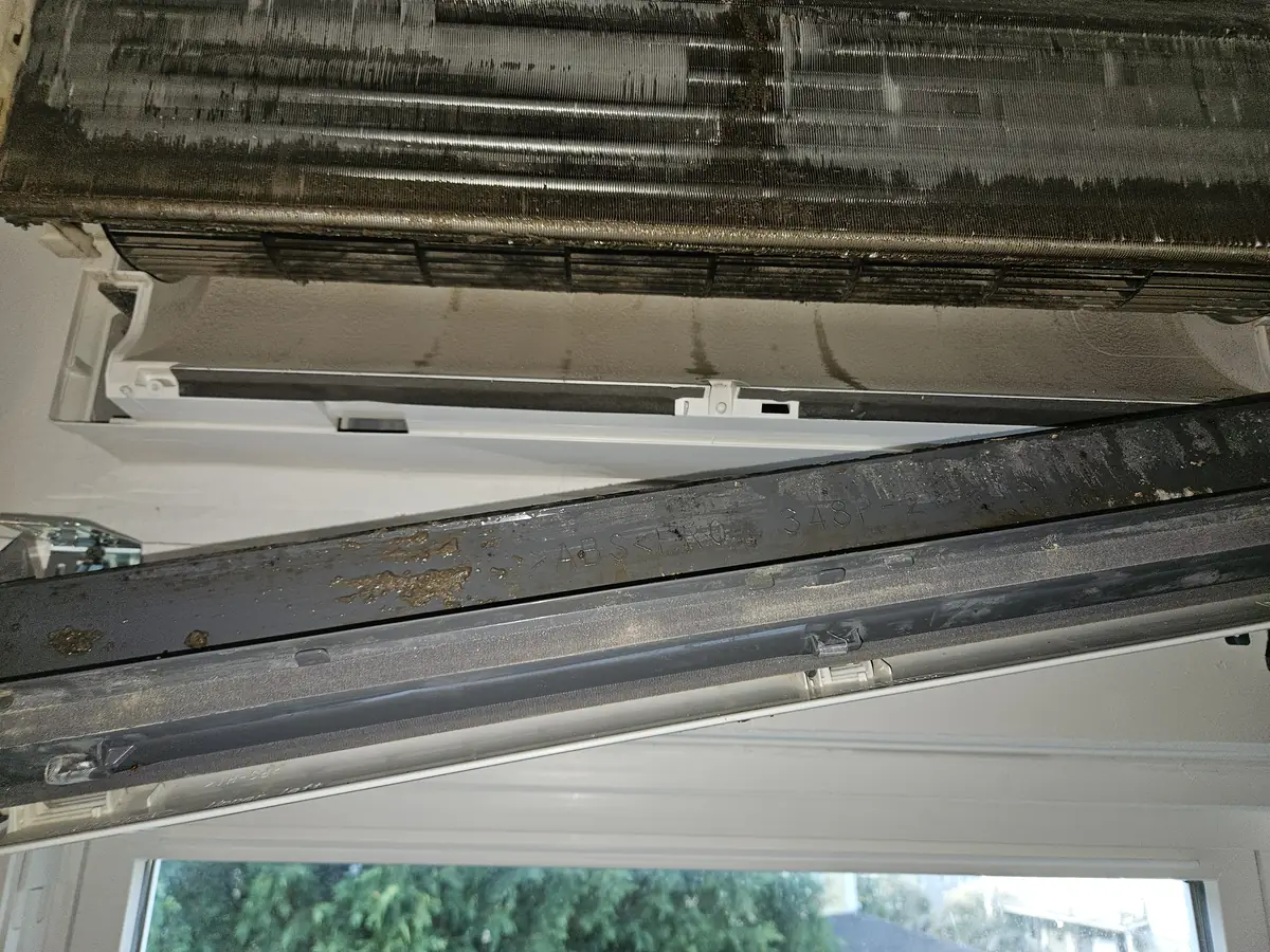 Heavily soiled evaporator coil and drain pan inside a Mitsubishi mini-split in Brighton, MA before cleaning