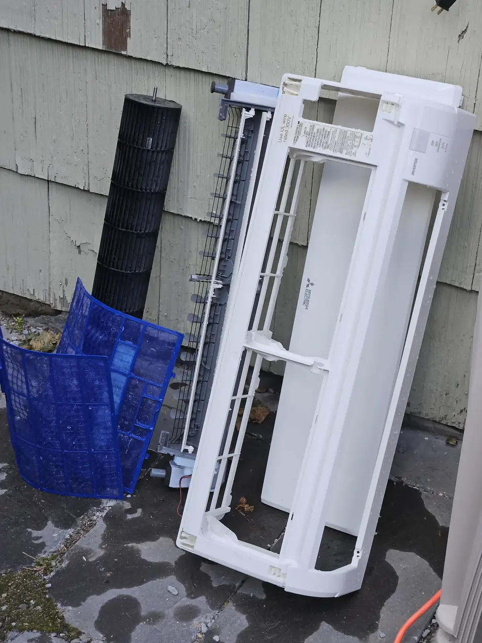 Washed mini-split parts drying against the siding of a Brighton MA multifamily home
